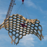 Photo of a huge free-form part, suspended from a crane during assembly