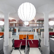Blick in die modern und hell eingerichteten Büroräumlichkeiten der Firma Givaudan. Es überwiegen die Farben Weiss und Rot. An der Decke hängen asiatische angehauchte Lampen. 