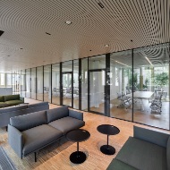 Le lounge avec des sièges d’un gris discret devant la grande façade vitrée permet des échanges informels