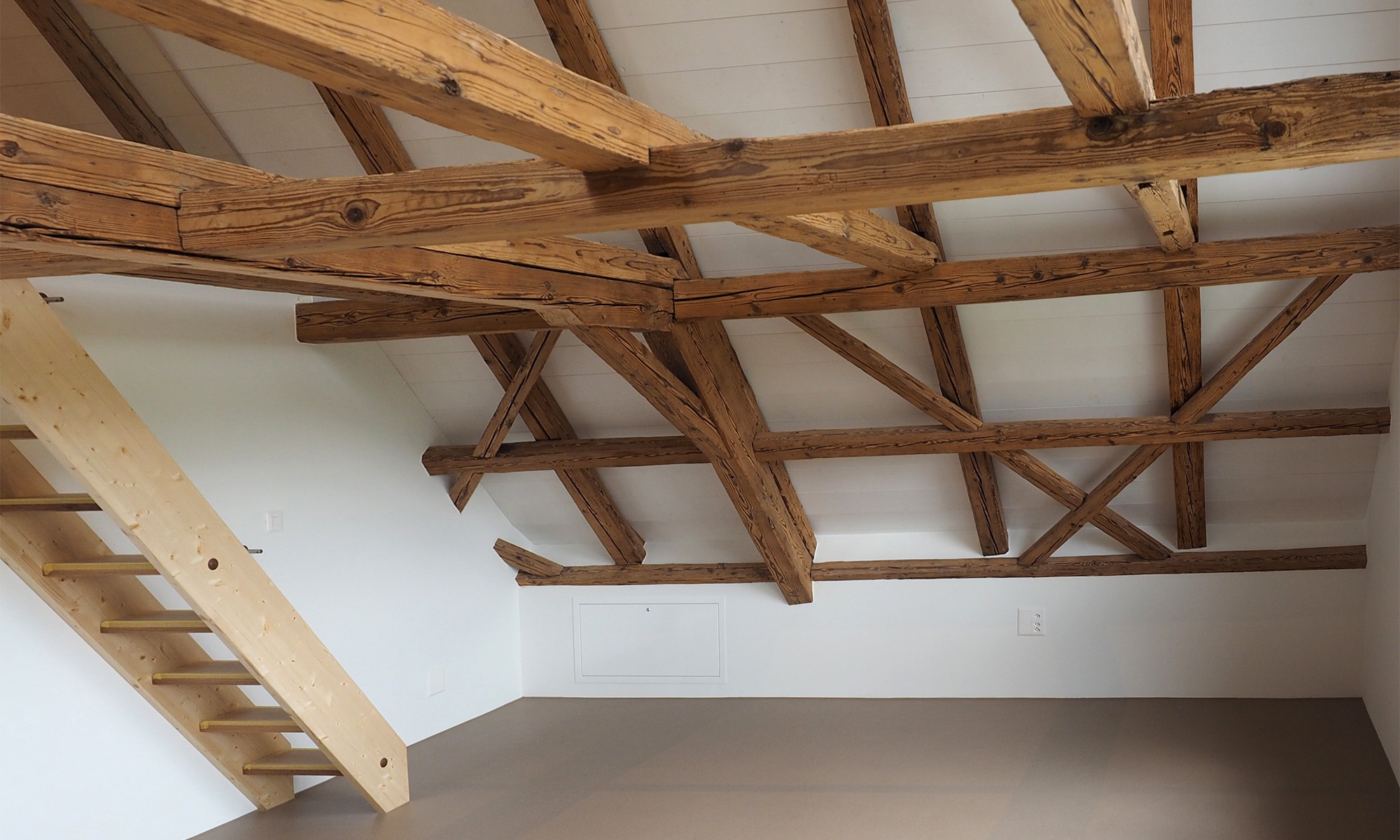 Dachgeschoss vom Einfamilienhaus verkleidet mit Holzbalken und einem kleinen Treppenaufgang