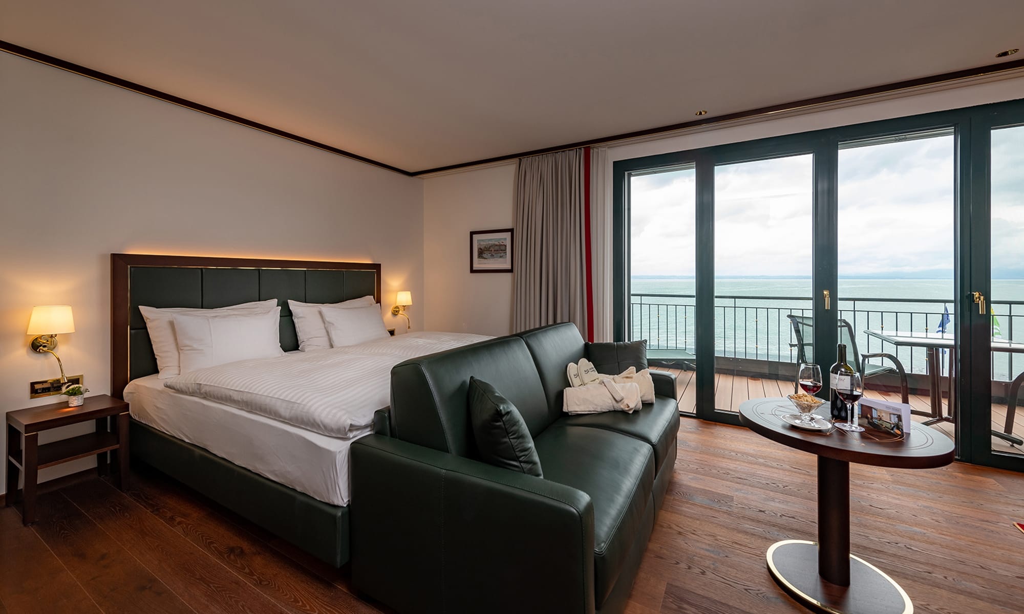 Blick ins Hotelzimmer mit Doppelbett, grosser Fensterfront und Balkon mit Sicht auf den Bodensee
