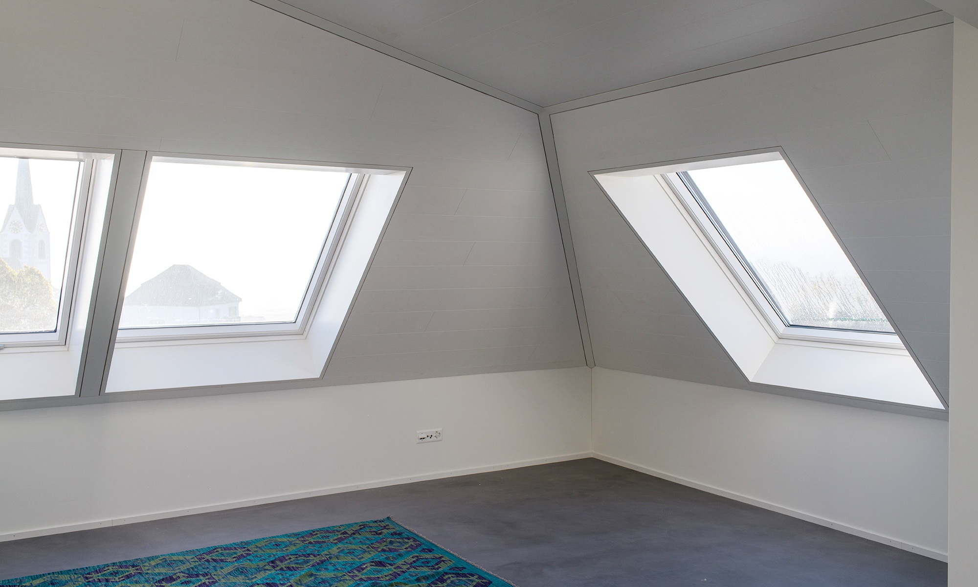 Helles, noch leerstehendes Dachgeschoss mit grossen Fenstern im Mehrfamilienhaus Berg.