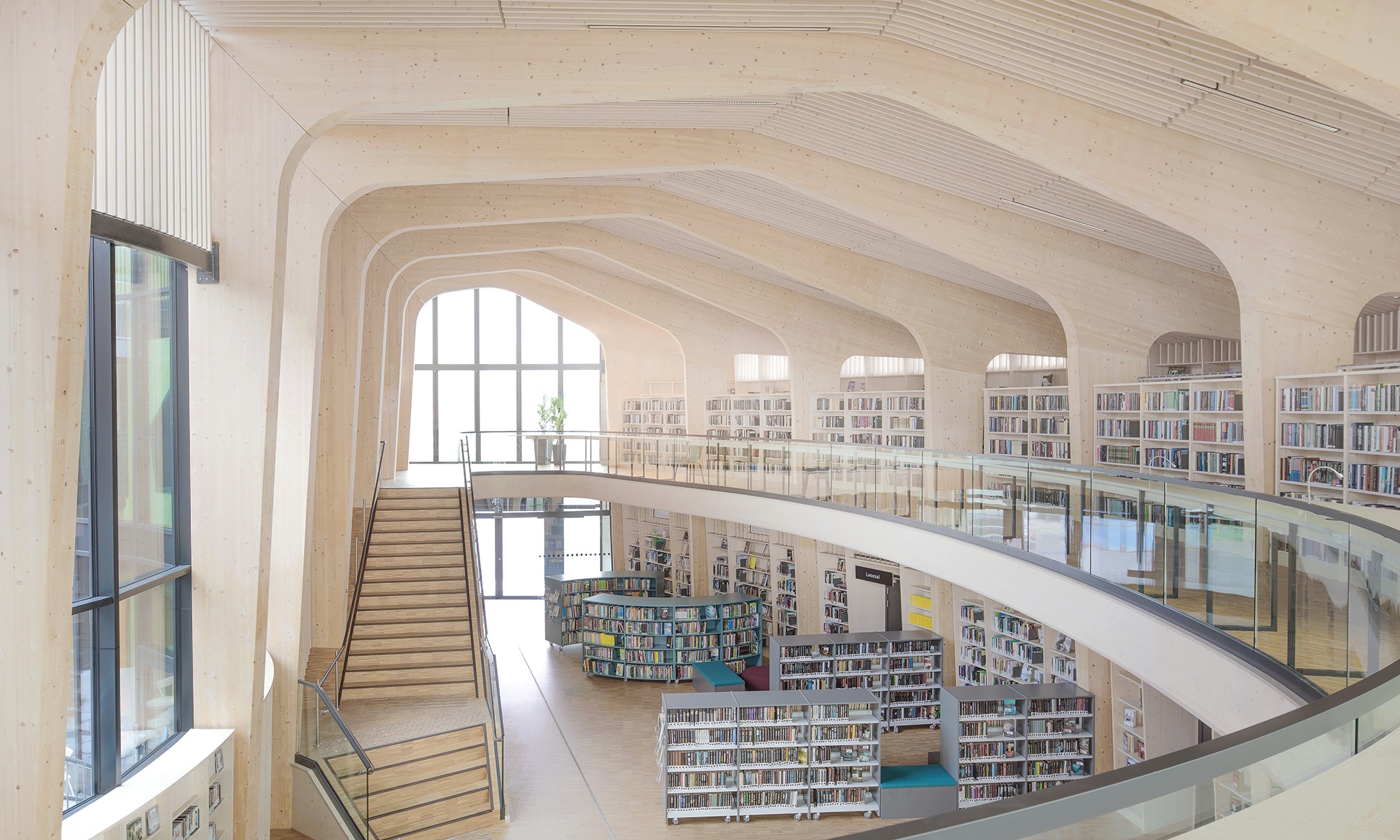 Blick von der Galerie in den grossen, hellen Raum mit Treppe und Bücherregalen 