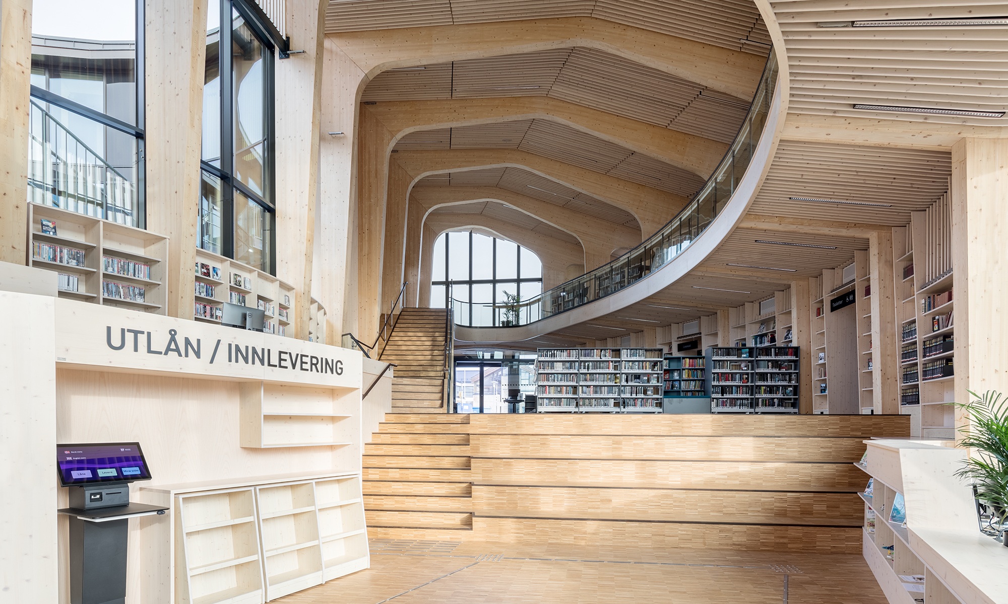 Bibliothèque avec galerie et étagères à livres dans une construction en bois courbée.