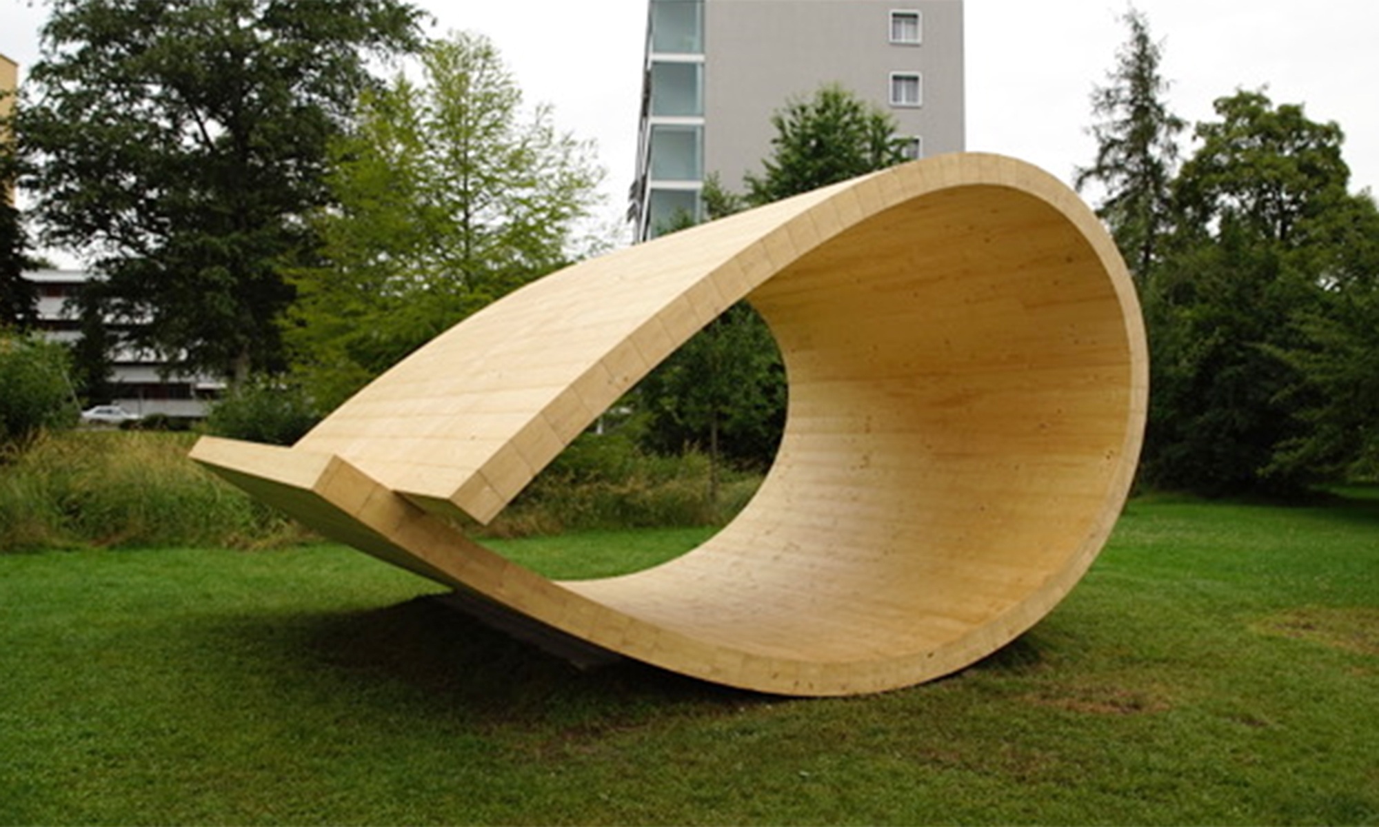 Der Klangraum-Pavillon ist eine Skulptur in Form einer Schlaufe aus Holz. Sie befindet sich in einem Park in Zürich.