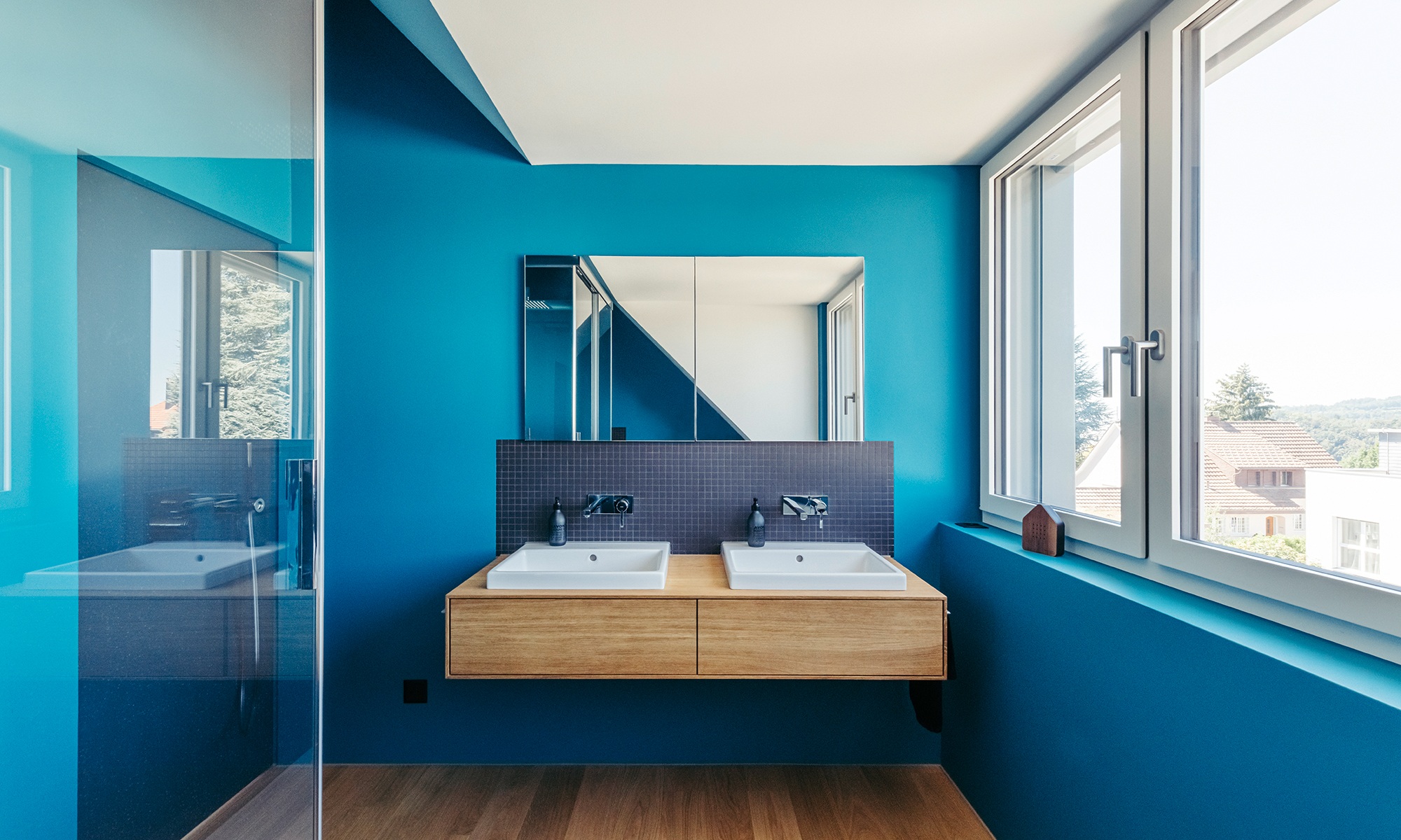 Badezimmer mit blauen Wänden, grosser Fensterfront und Doppellavabo