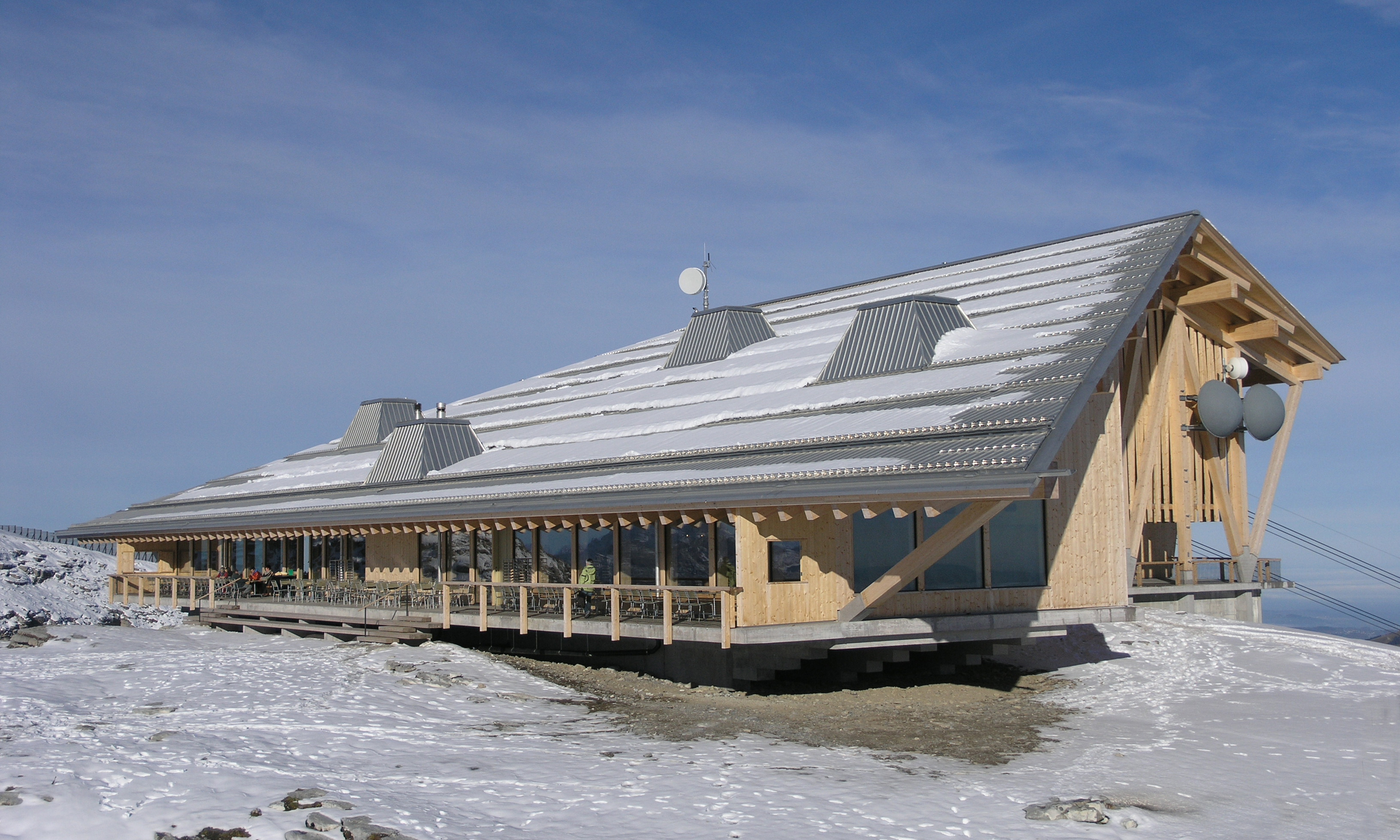 Aussenansicht Berggasthaus Chäserrugg mit Schnee auf dem Dach und schneebedecktem Boden. 