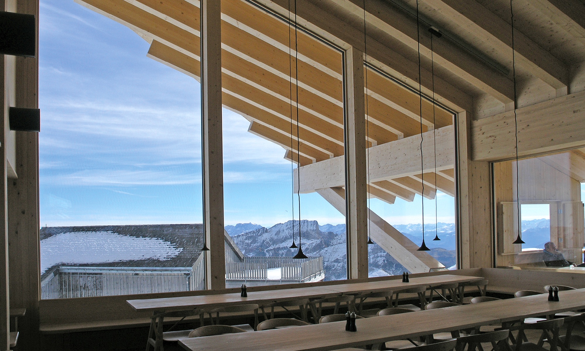 Essbereich Berggasthaus Chäserrugg mit Tischen und Bestuhlung sowie Ausblick auf Bergpanorama bei blauem Himmel