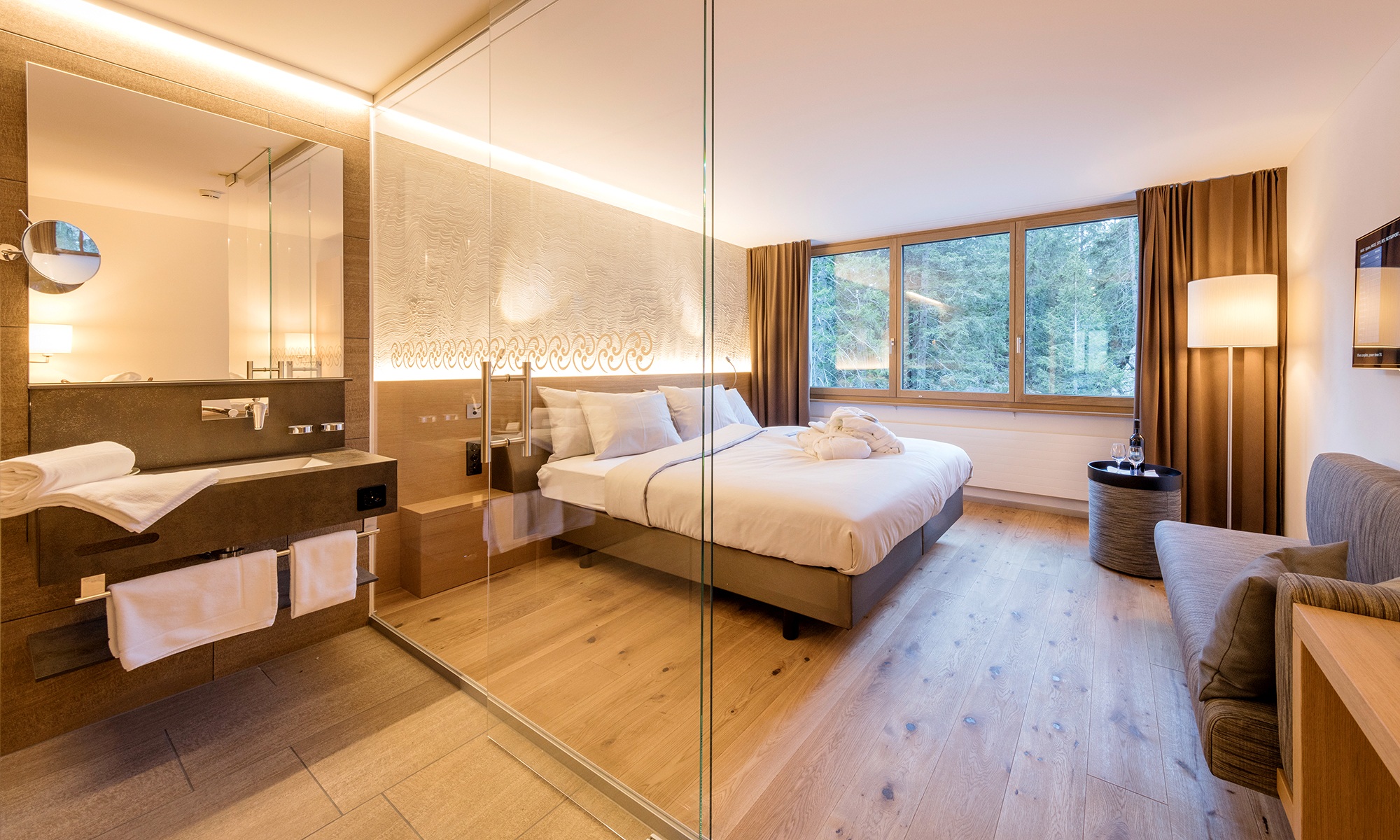 A glazed door separates the spacious bedroom from the bathroom. The room is furnished to a high standard and is bathed in light thanks to the large window.