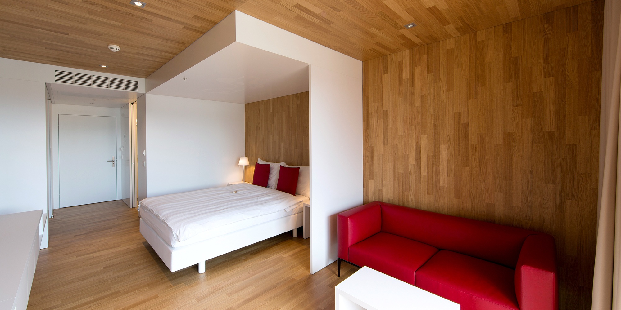 Le sol, les murs et le plafond de cette chambre de l’hôtel Säntispark sont revêtus du même bois. La chambre lumineuse est équipée d’un mobilier moderne.