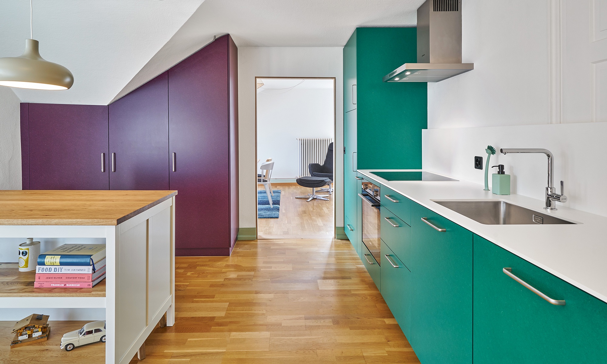Einbauküche mit farbigen Schrankfronten sowie Fussboden aus Holz