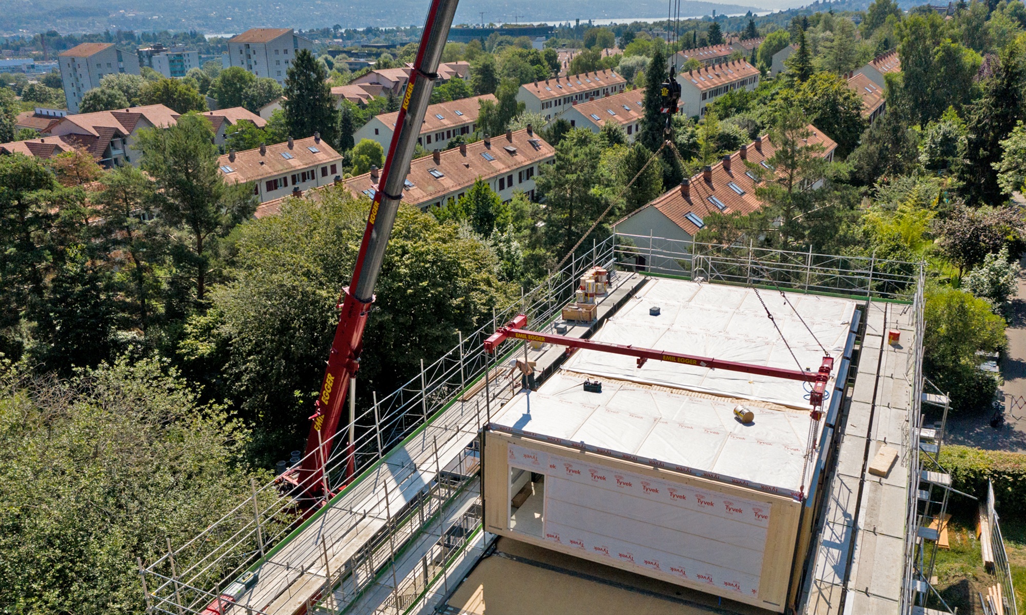 Blick aus der Luft auf das Dach des Schulhauses Friesenberg mit fünf bereits platzierten Holzmodulen auf dem Dach.
