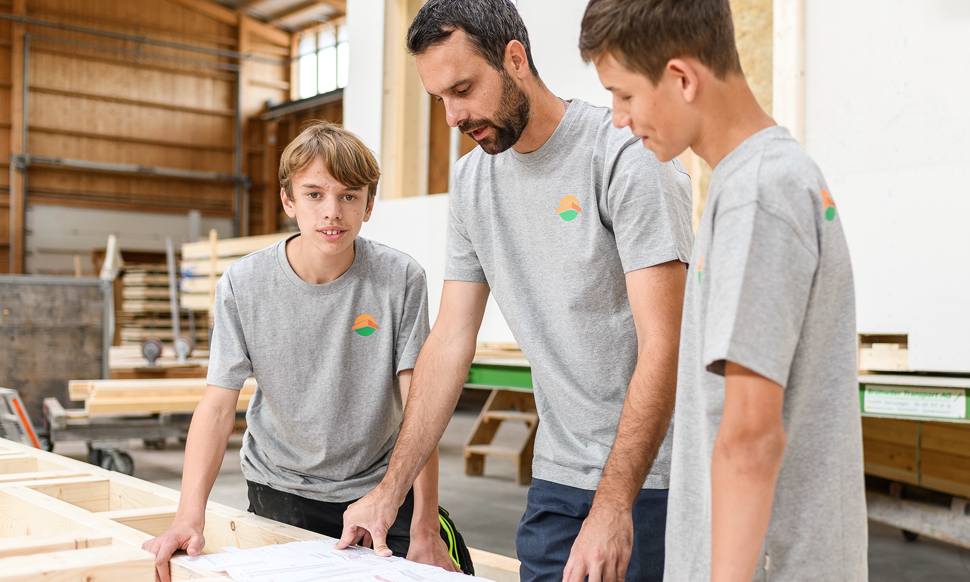 A group of 2 apprentices and an instructor, mid-discussion. One person is looking at the camera, 2 are looking at a diagram.