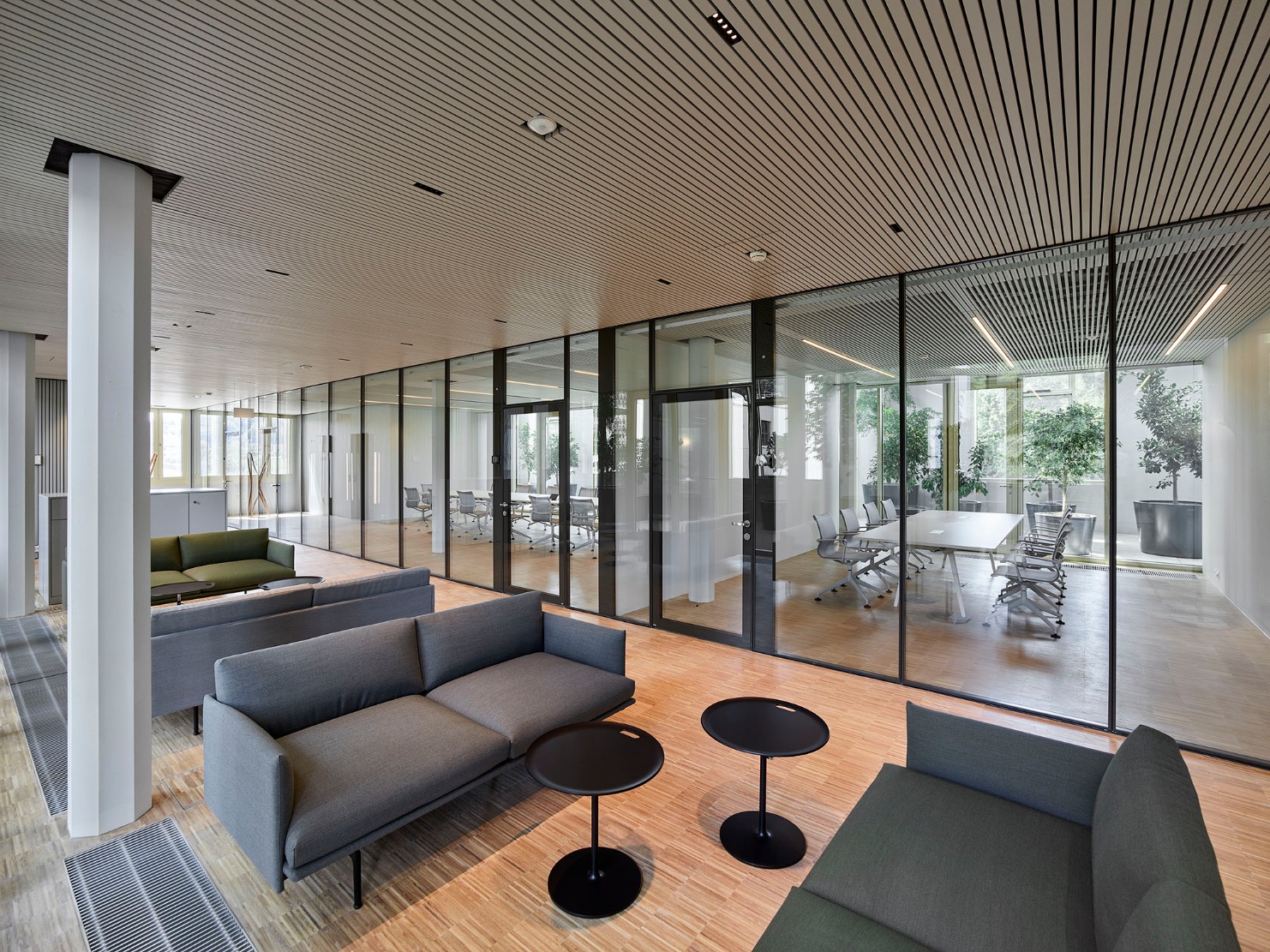 Le lounge avec des sièges d’un gris discret devant la grande façade vitrée permet des échanges informels