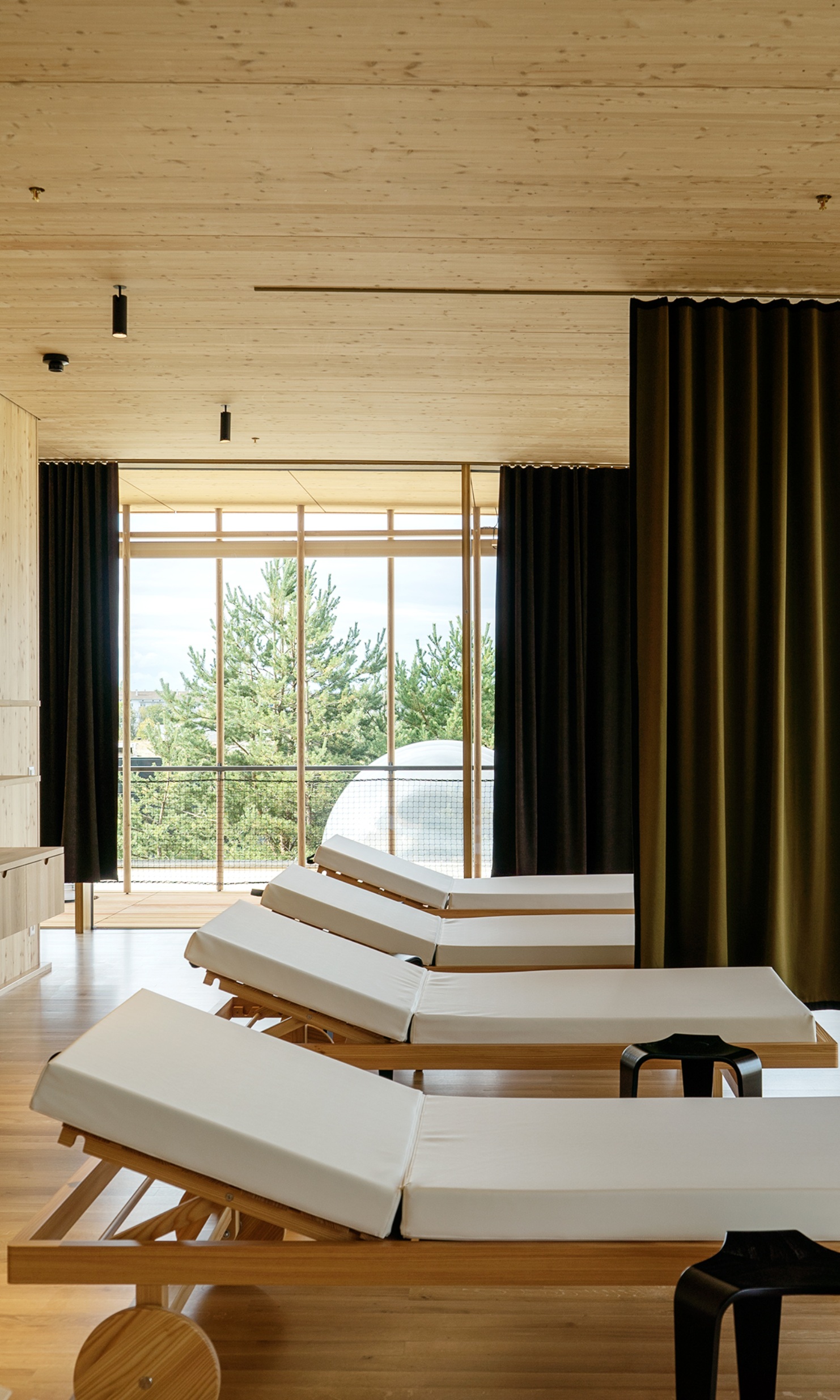 Looking into the bright relaxation room, with four loungers and dark curtains to break up the space