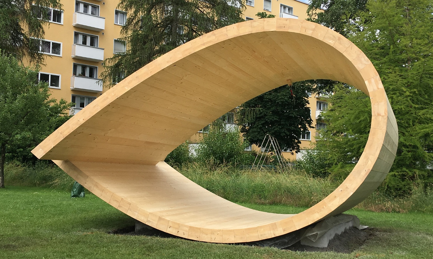 The sound space pavilion is a sculpture in the shape of a loop made of wood. It is located in a park in Zurich.