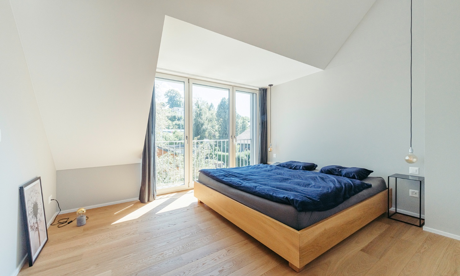 Chambre lumineuse avec lit double et plancher en parquet dans la maison individuelle surélevée
