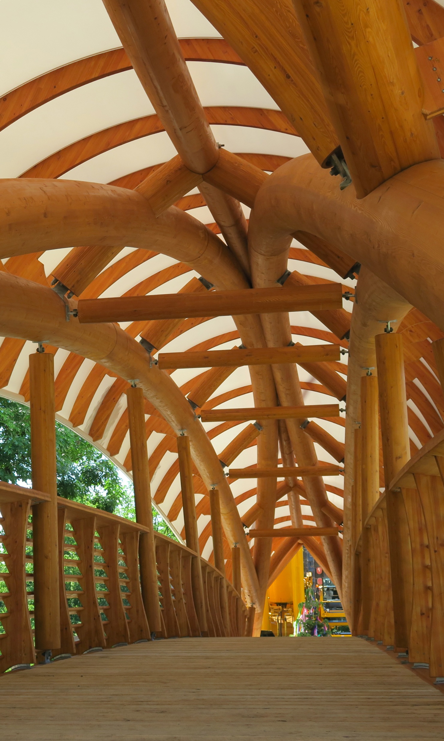 L’intérieur du pont artistique en bois «Aubrugg» est visible. On distingue des structures courbes en bois massif et un garde-corps haut en bois.