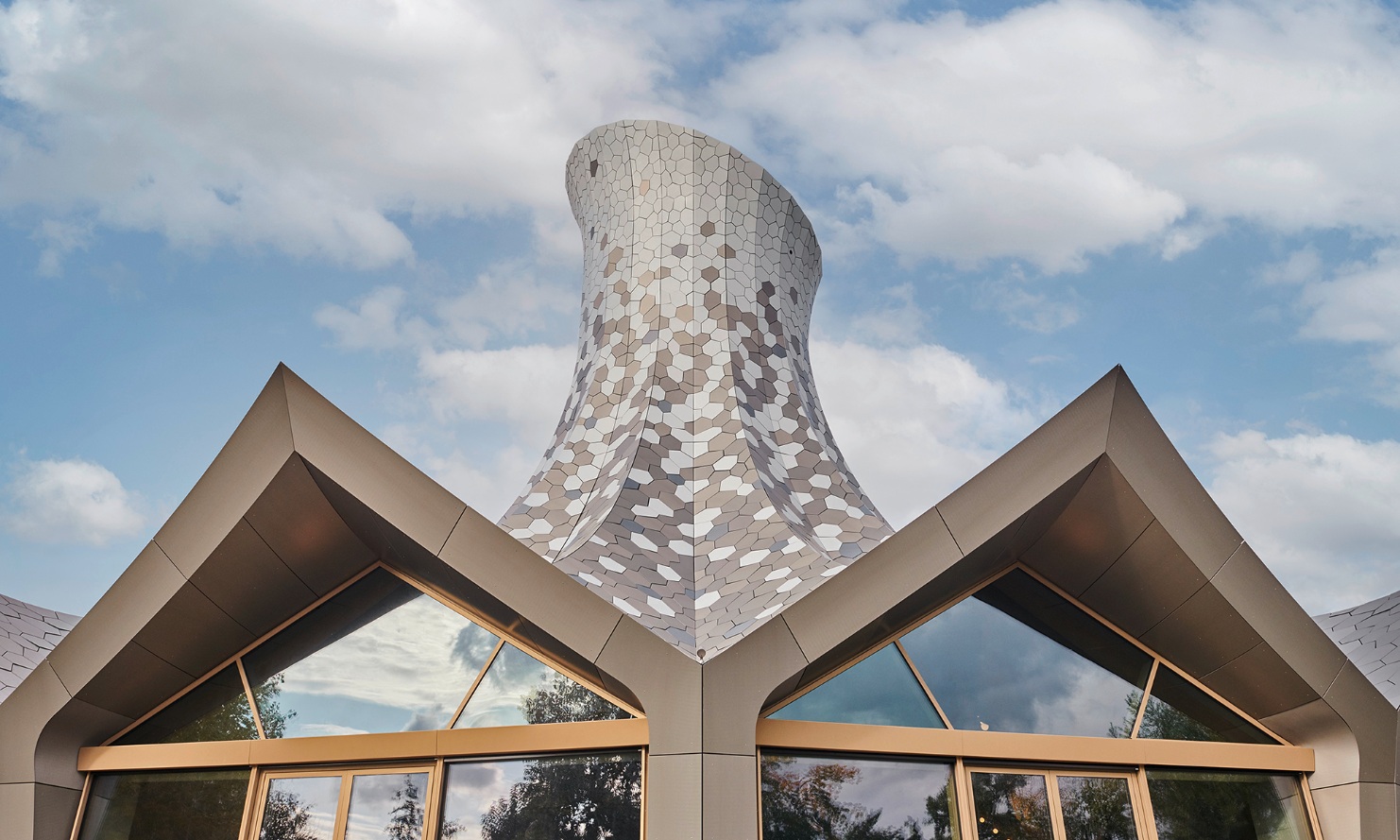Des écailles métalliques de forme irrégulière recouvrent le toit autoportant, qui est conçu comme une structure pliante.