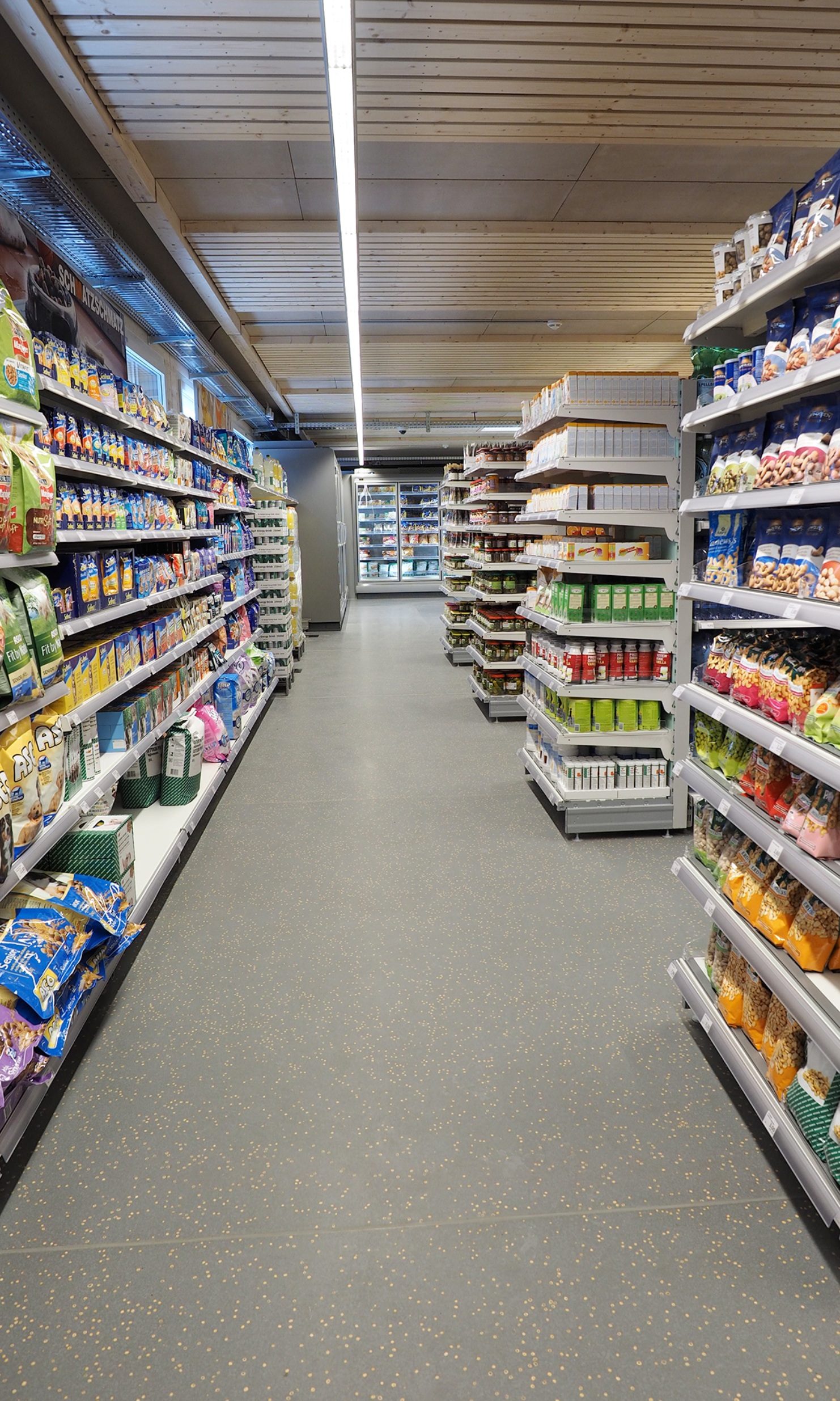 Interior view of the Migros temporary store; corridor with shelves on both sides.
