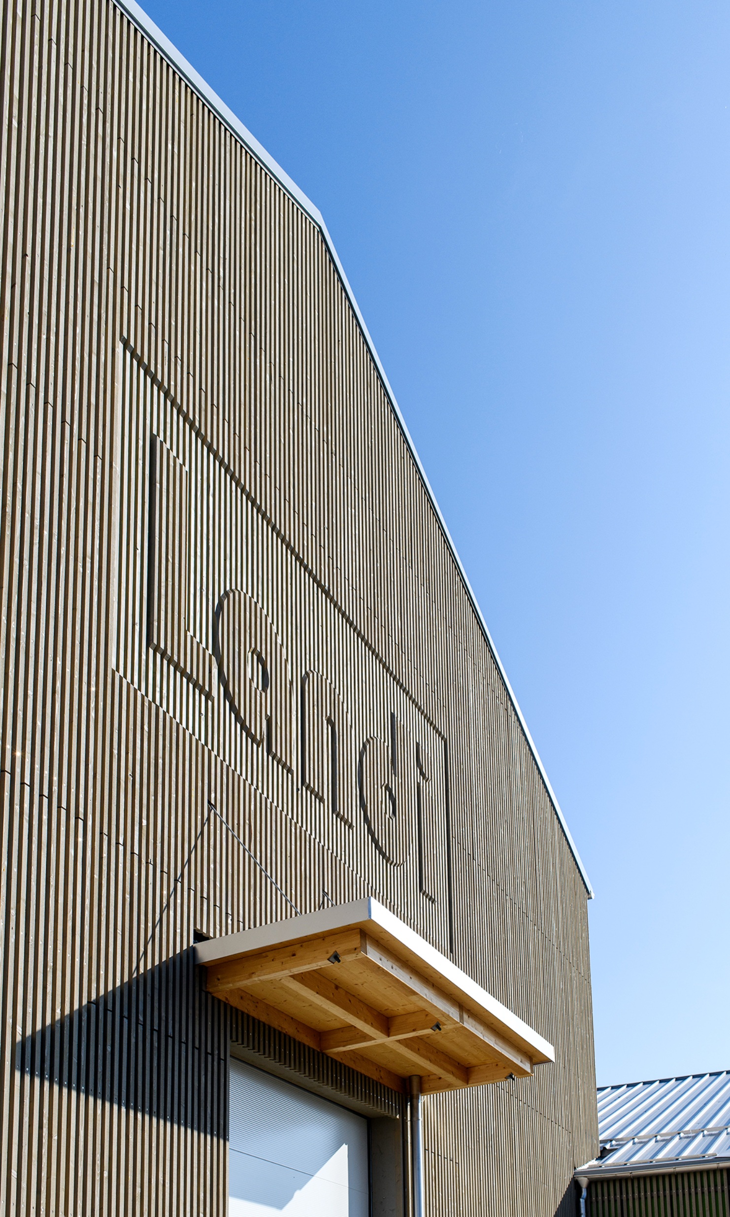 The photograph shows the facade with the address of the Landi branch processed in wood.