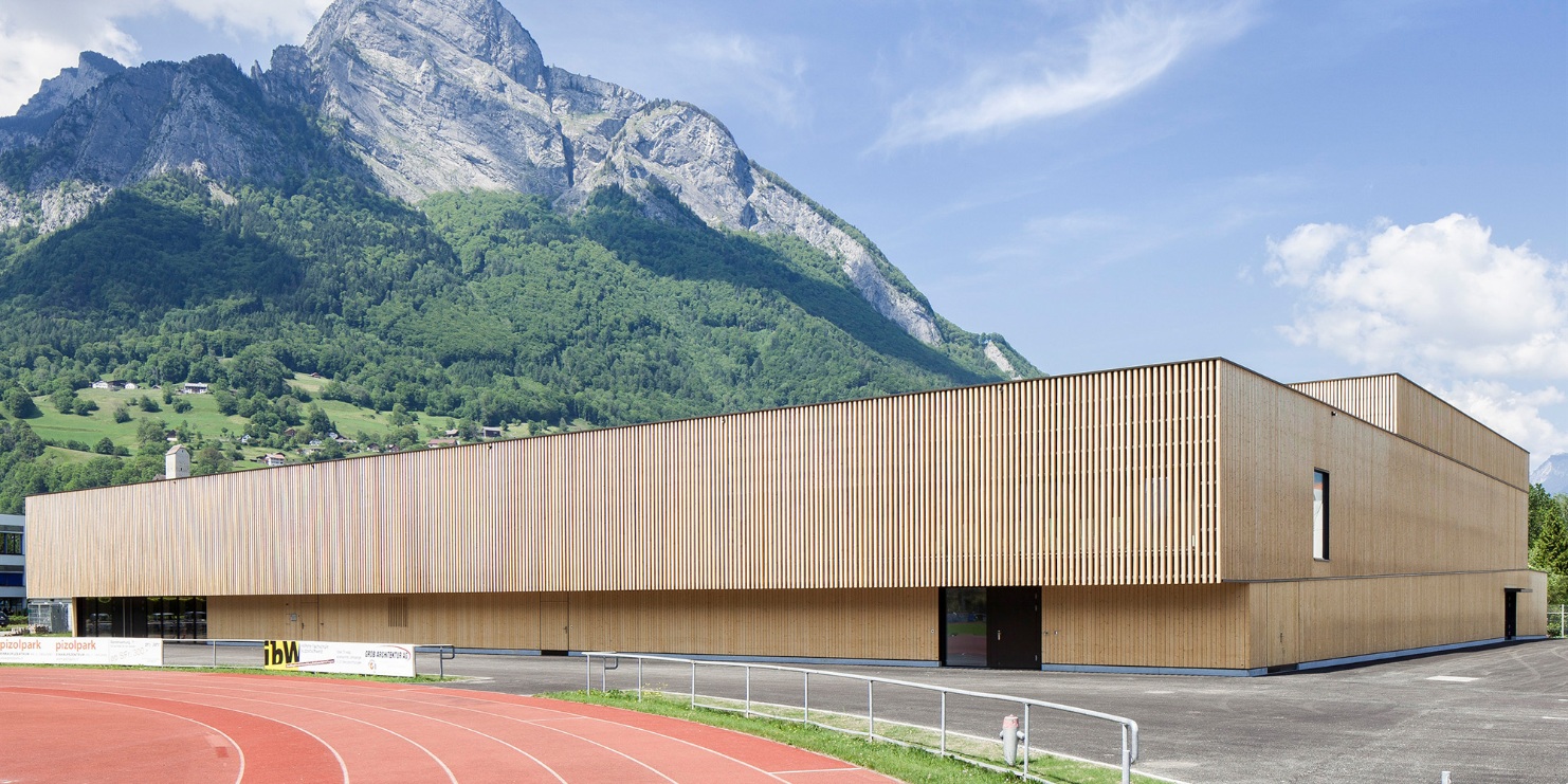 RSA Sargans sports hall with tartan track in the foreground and mountain backdrop.