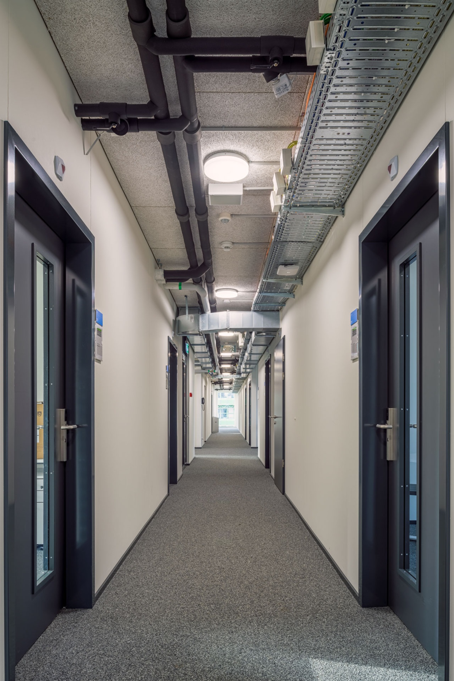 Corridor in the UNIL temporary office building with exposed services.