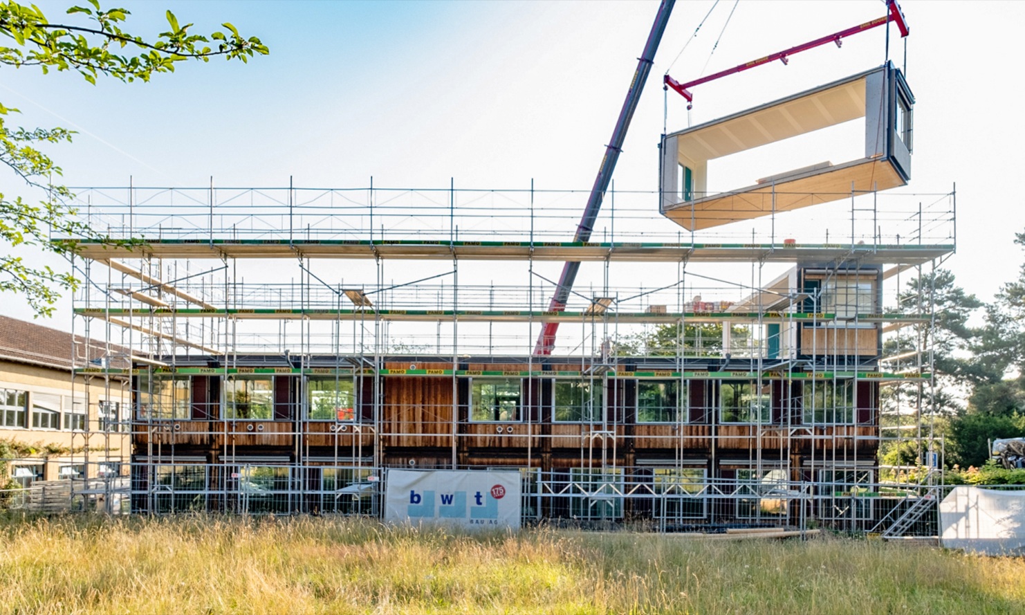 The existing ZM10 modular Friesenberg primary school is extended by adding another floor. A timber module is placed on the roof by crane. 