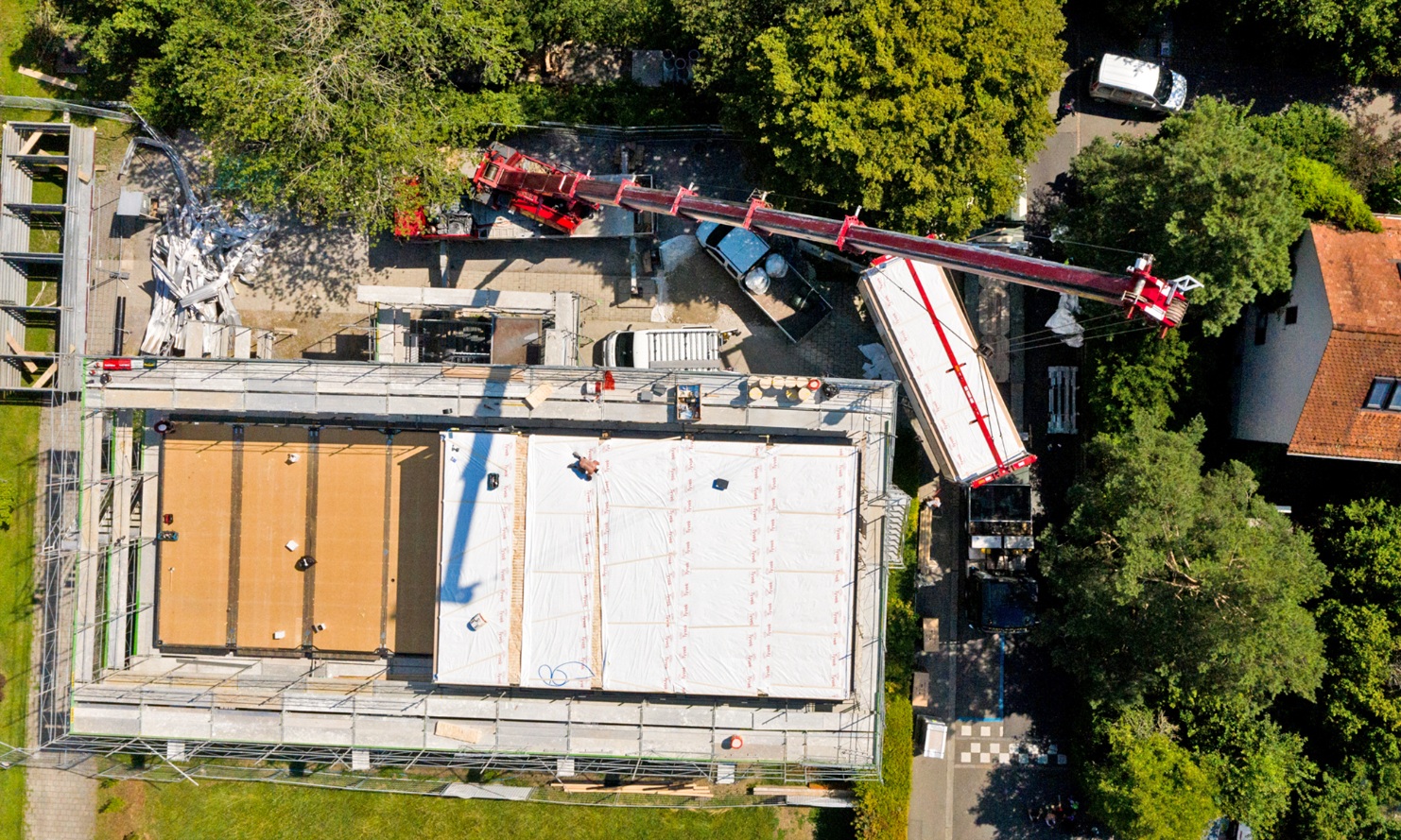 Aerial photograph – from above, it is possible to see the five timber modules already hoisted by crane onto the roof of the school building and moved into place.