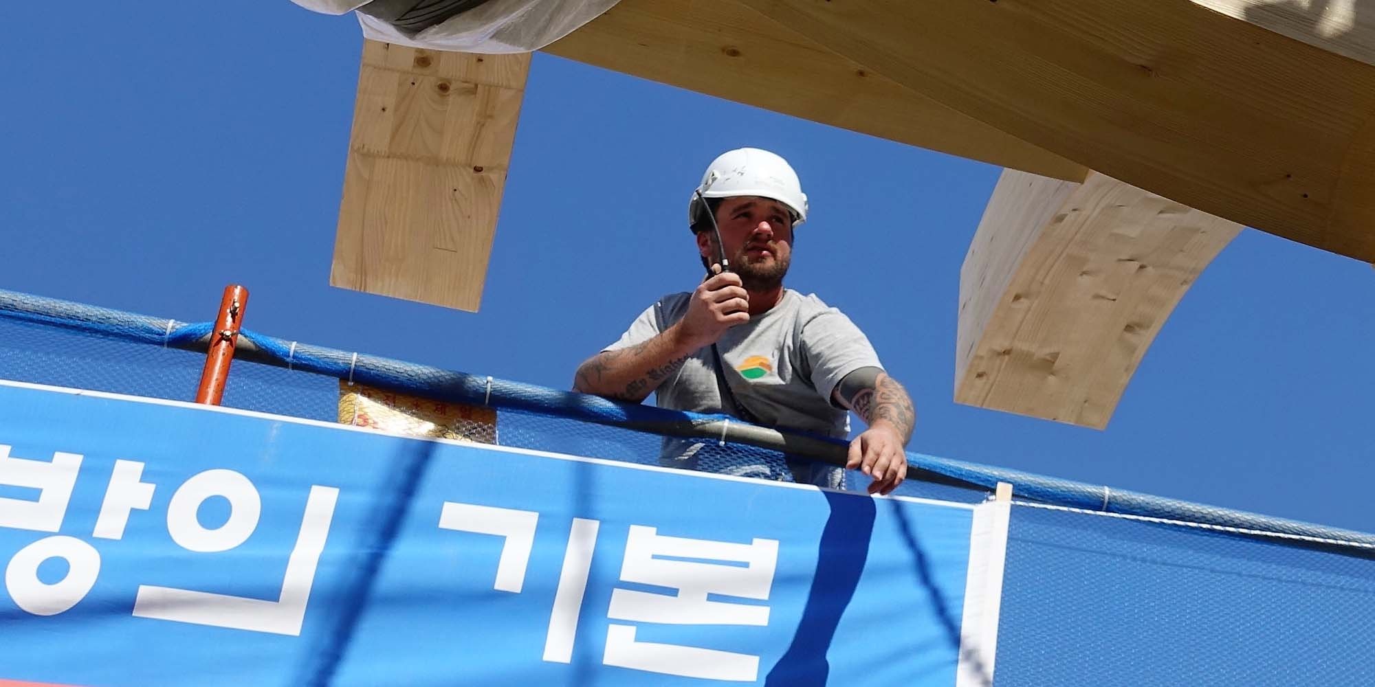 Carpenter/installer on an international construction site holding a radio