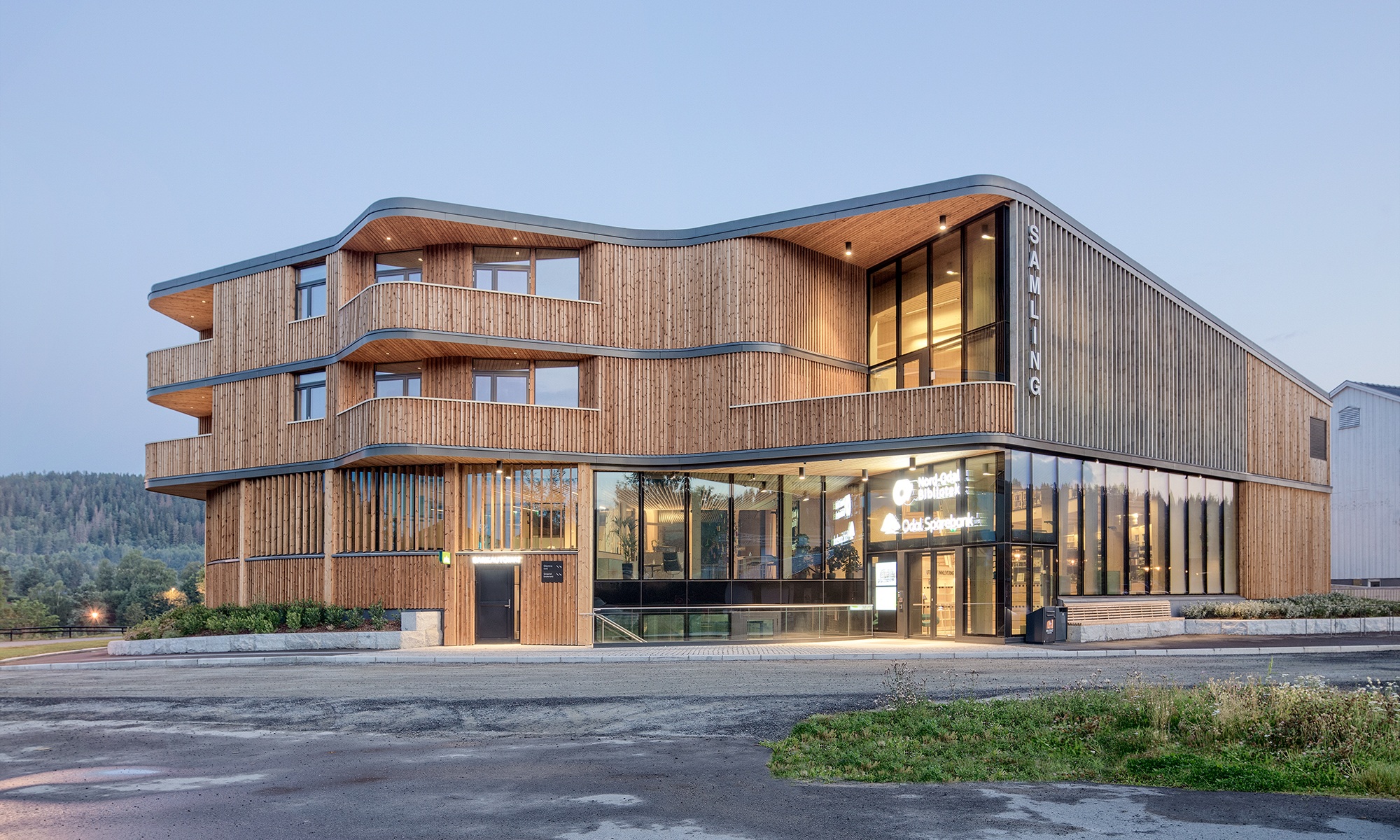 Dreistöckiges Bibliotheksgebäude Samling mit geschwungener Form in Holzbauweise bei Abendstimmung