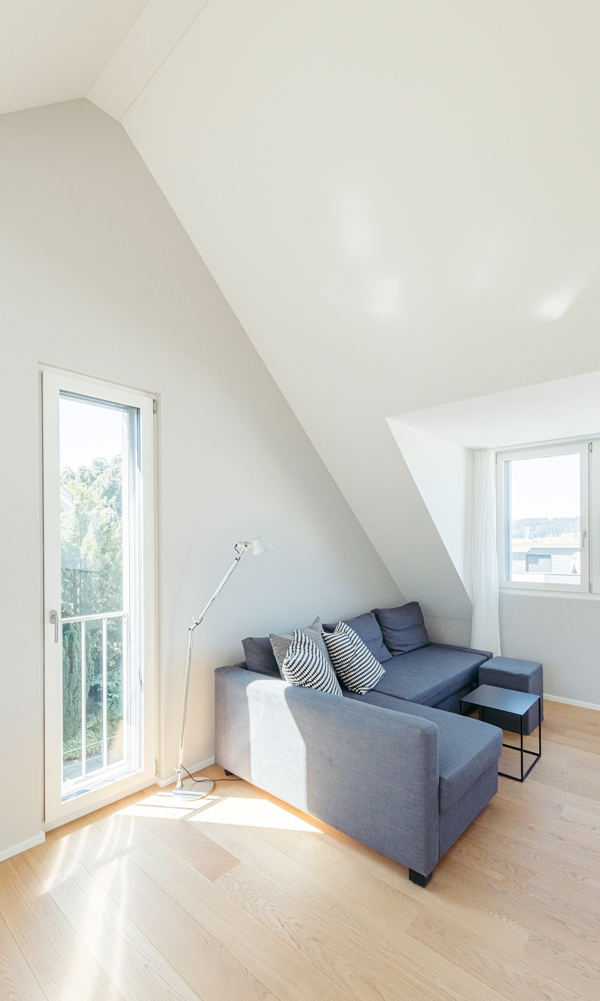 Sitzecke mit grauem Sofa im hellen Wohnbereich mit Parkettboden im aufgestockten Einfamilienhaus
