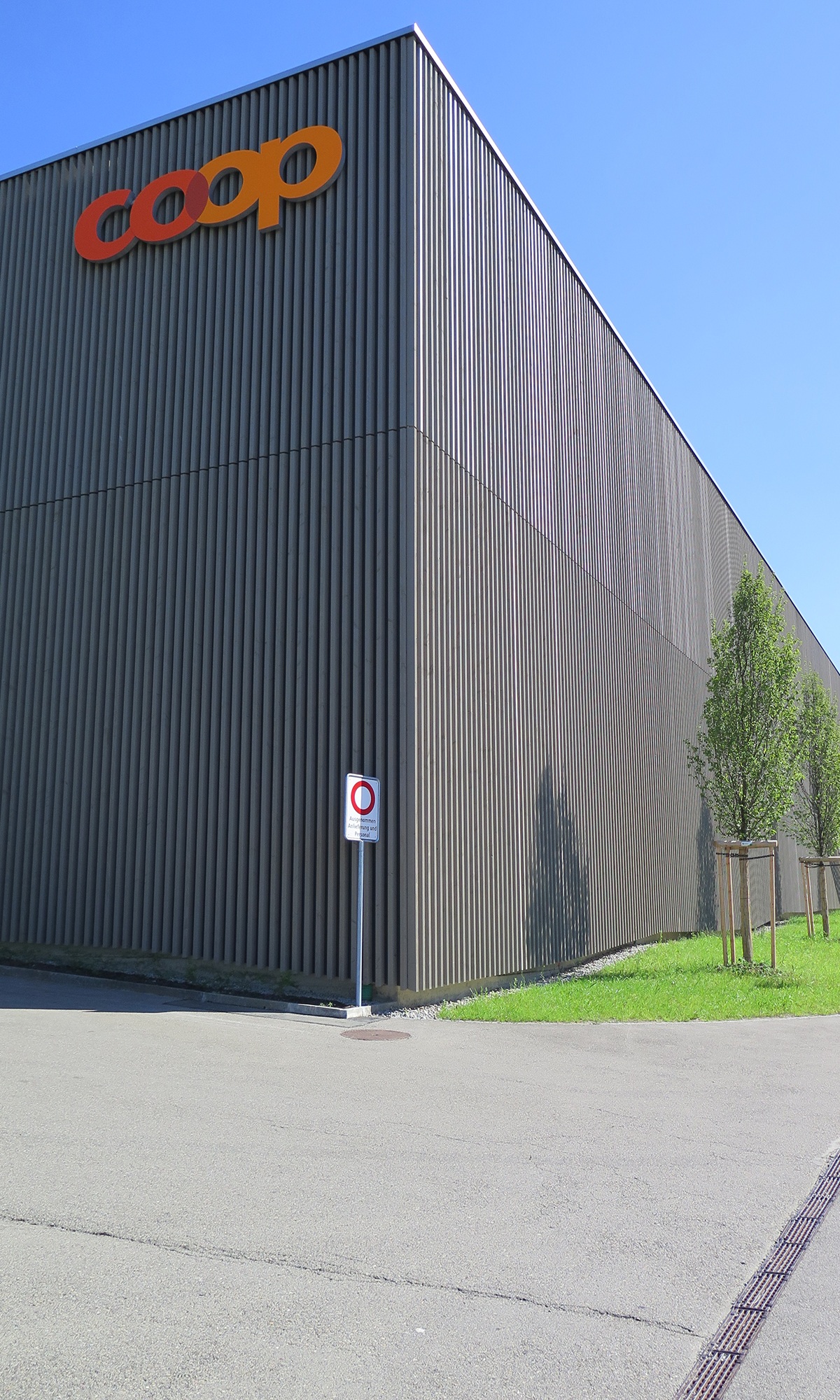 Detailansicht der schlichten dunklen Holzfassade des Coop Super Centers Uzwil mit markantem Logo.