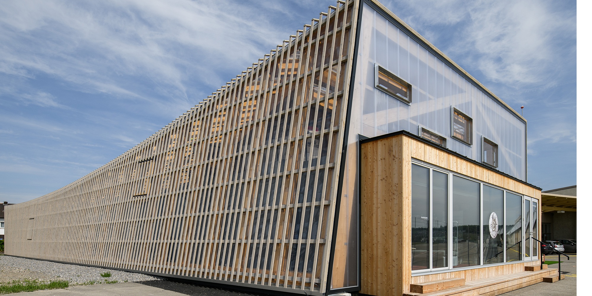 Side view of the Switzerland Innovation Park in Dübendorf with view of the covering structure comprising wooden slats and a membrane.