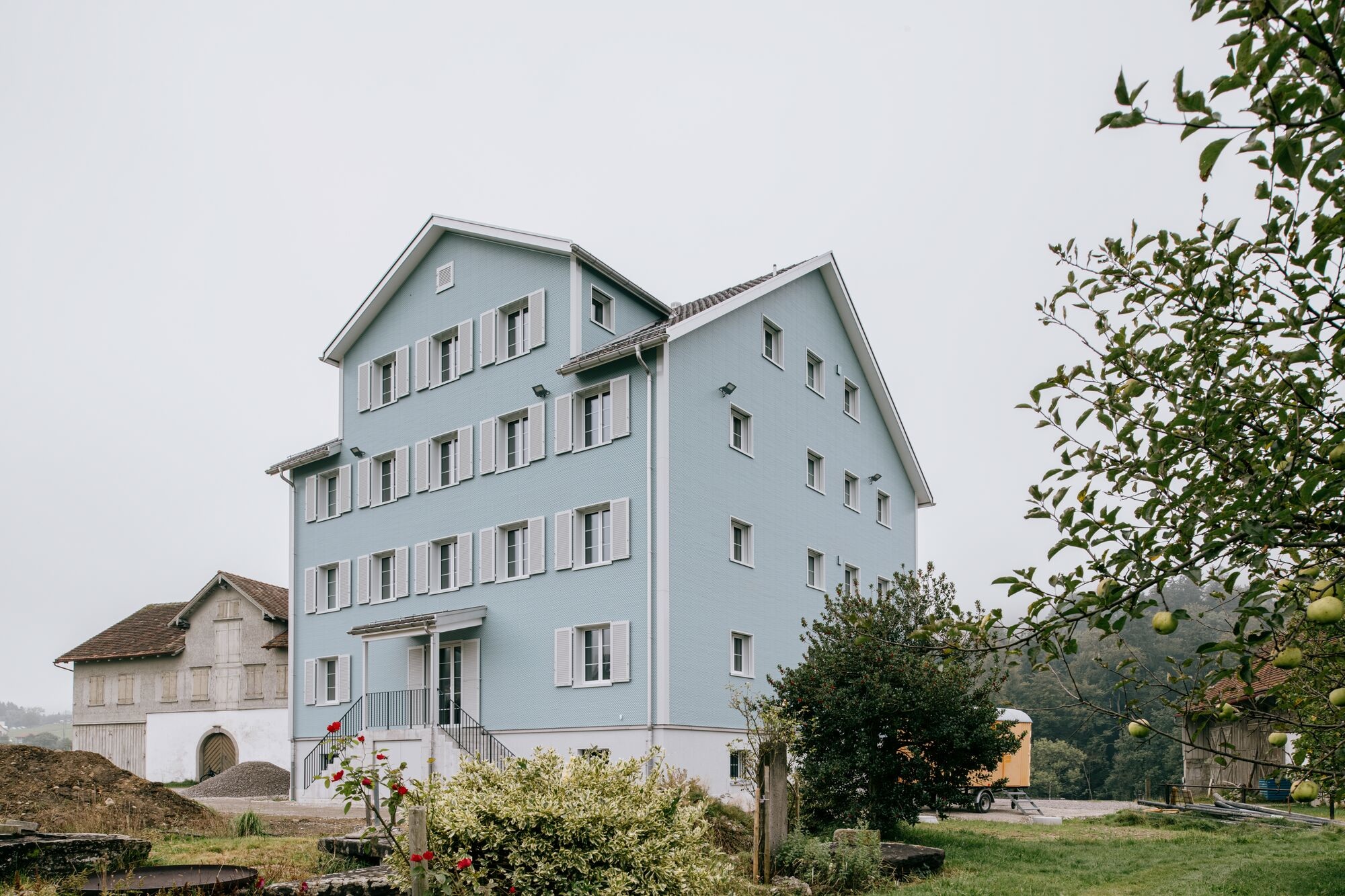 Viergeschossiges Mehrfamilienhaus mit hellblauer Eternit-Fassade