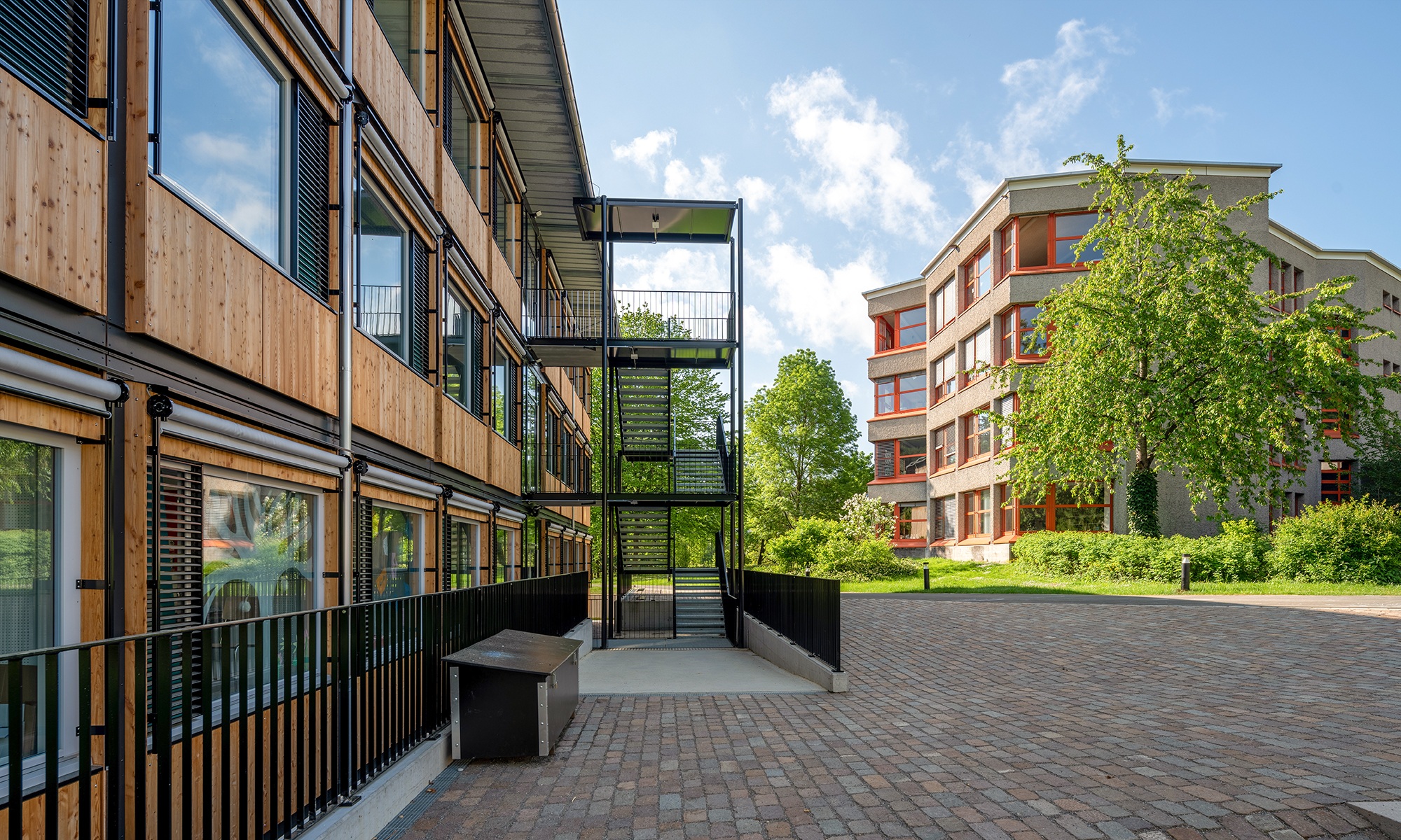 Escalier externe et façade du pavillon scolaire ZM10 à Zurich avec l'Ecole en arrière-plan