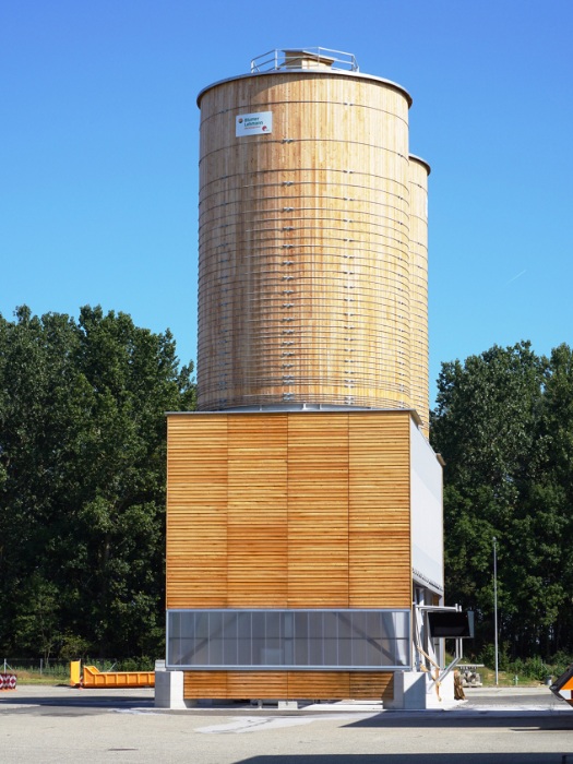 Round wooden silos for winter maintenance in Domdidier with a façade made of larch inverted formwork and polycarbonate light panels
