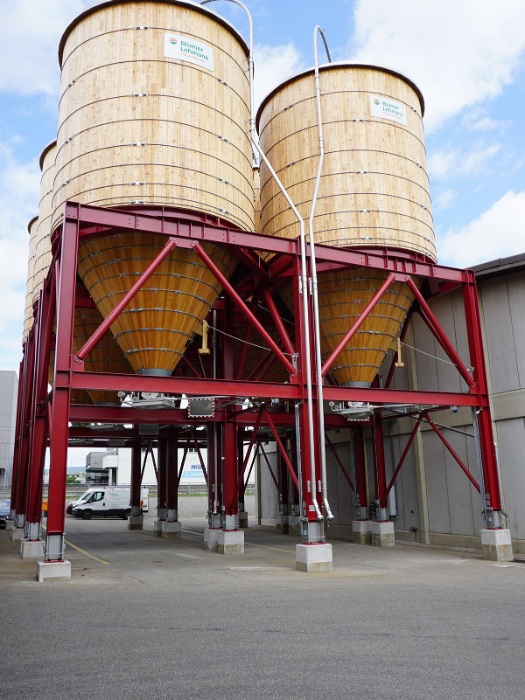 Six wooden grit silos of 200m3 each made of larch on a cubic, hot-dip galvanised and duplexed steel substructure.