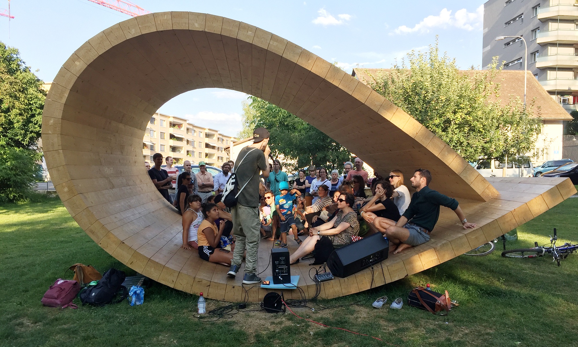 Many people sit or stand together in the sound pavilion, which is in the shape of a loop.