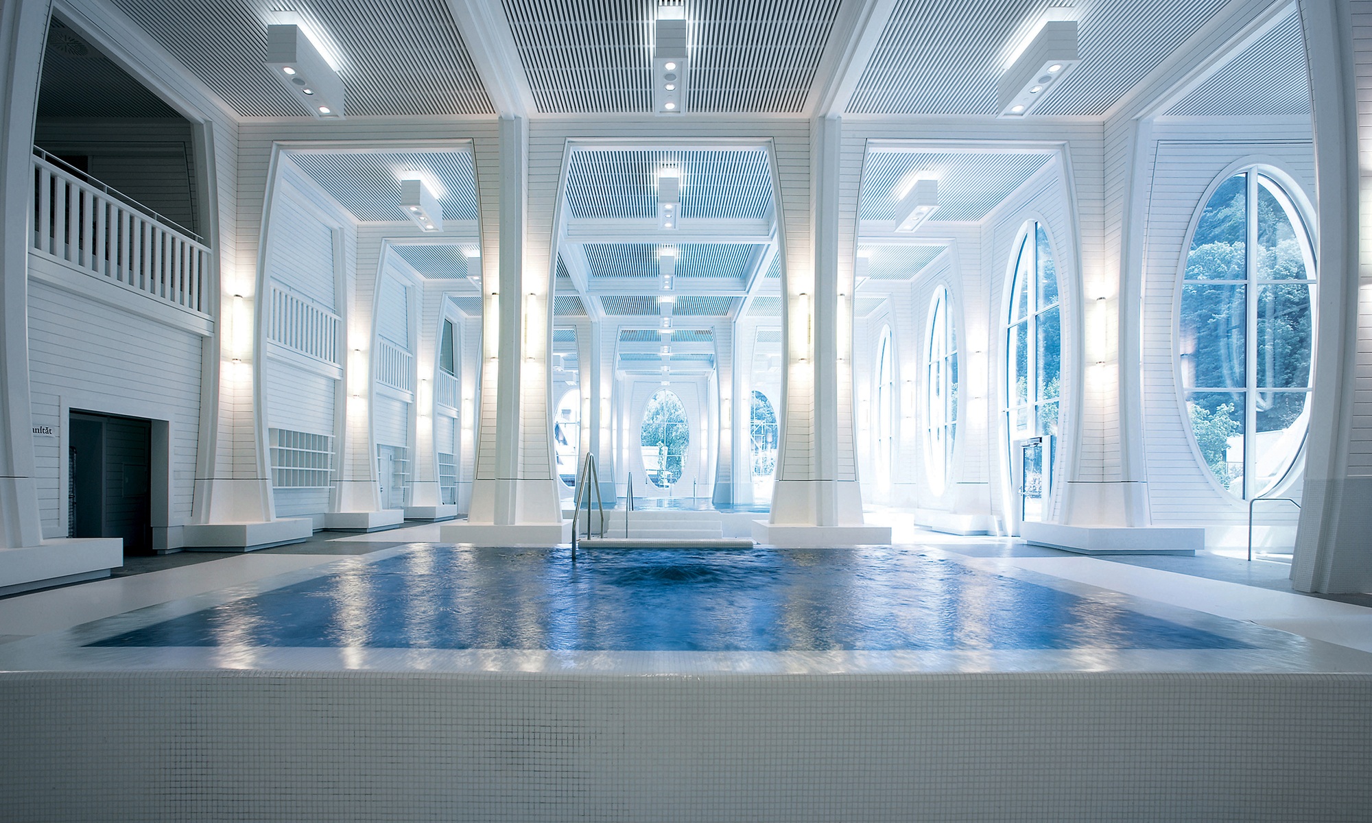 Swimming pool in a room with white columns and wooden ceiling cladding