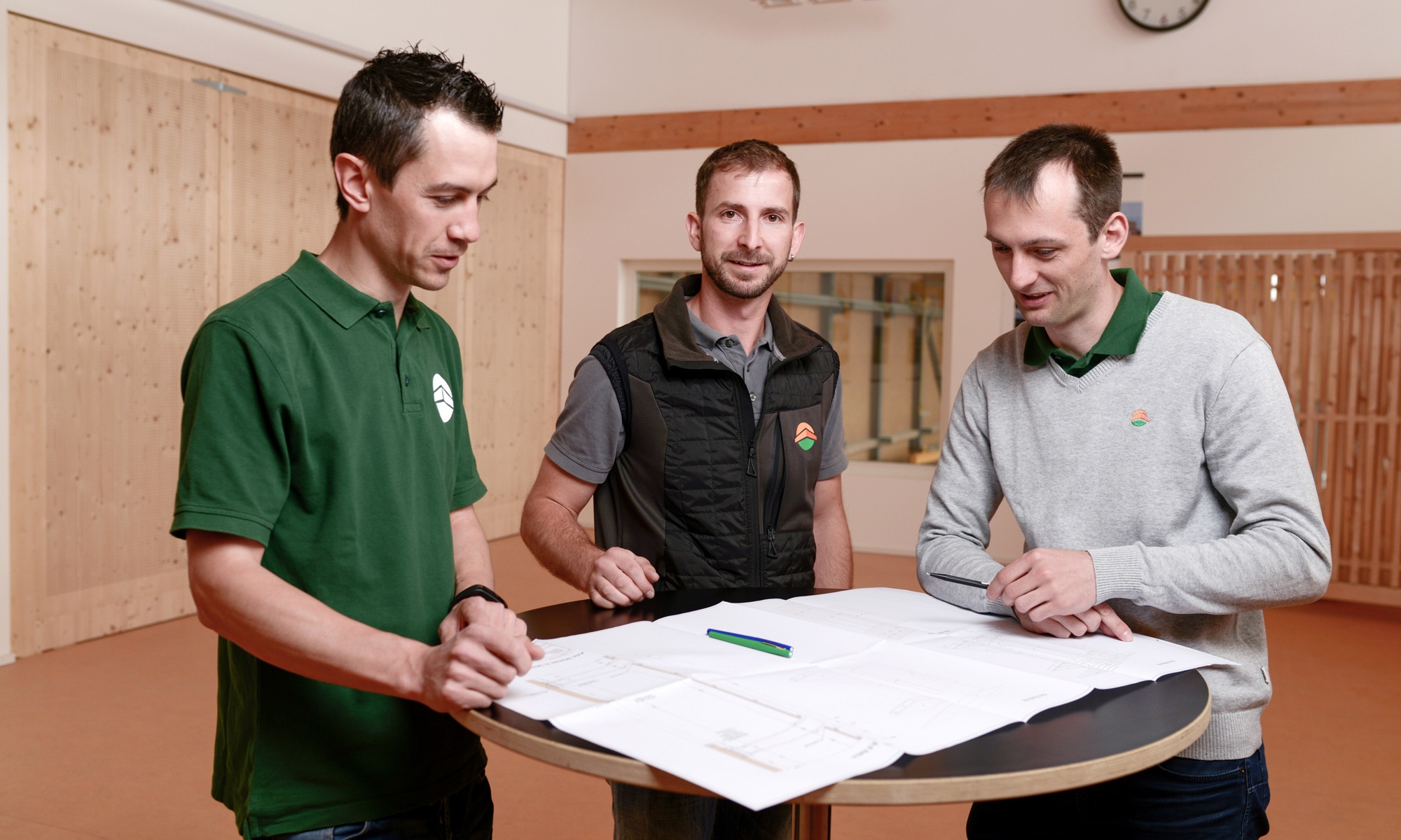 Drei Projektleiter stehend in einem Büro während einer Besprechungssituation
