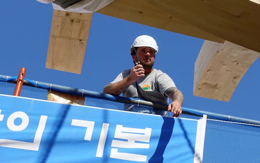 Monteur charpentier sur un chantier international avec un appareil radio à la main