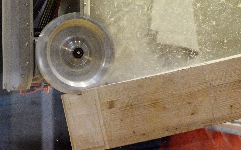 The milling head processes the piece of wood on the CNC machine. The shavings fly off.