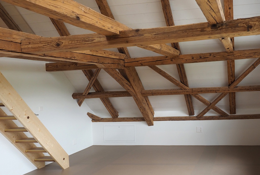 Attic of the single-family house clad with wooden beams and a small staircase
