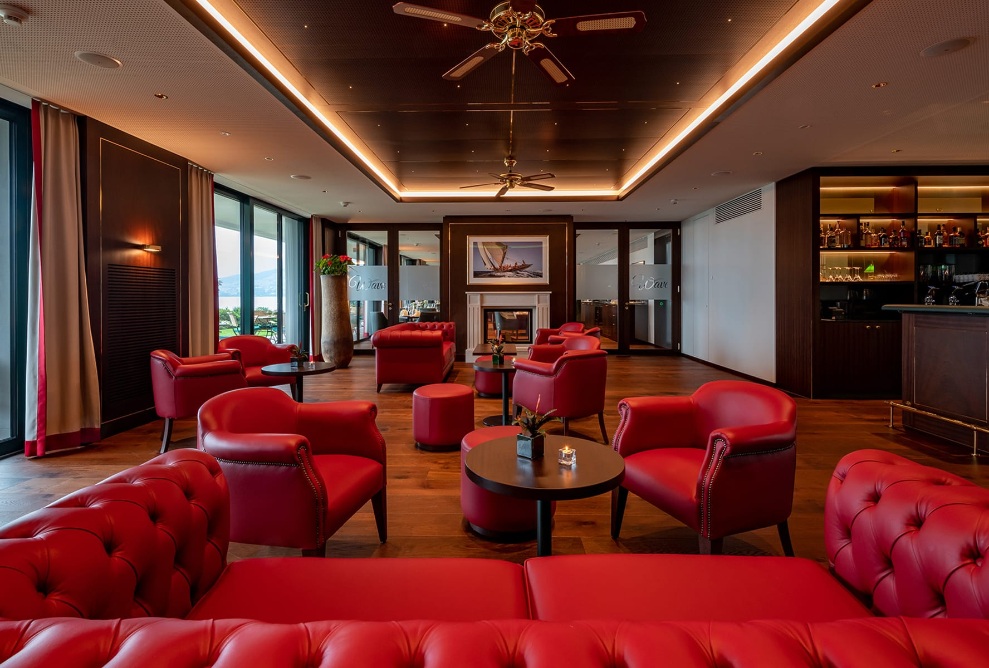 Lounge and bar at the Hotel Bad Horn with red sofas and armchairs, and indirect overhead lighting 