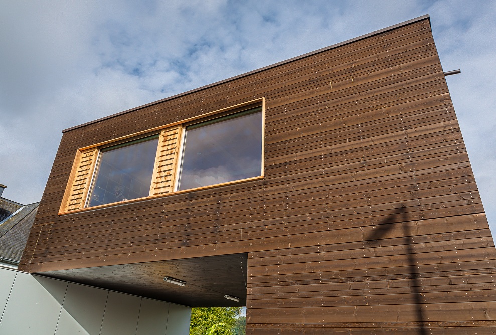 La façade en bois foncé de la construction modulaire vue d’en bas.