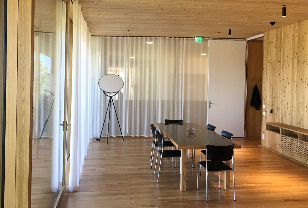 A table and six chairs in the spacious meeting room with timber walls, ceiling and floor.