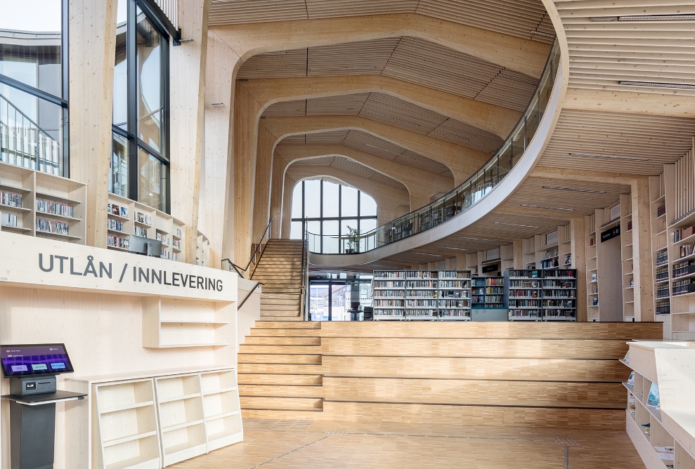 Bibliothèque avec galerie et étagères à livres dans une construction en bois courbée.