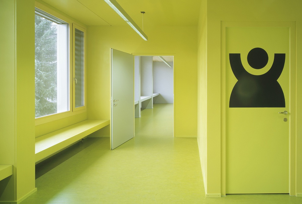 Le couloir coloré en jaune et le grand pictogramme sur la porte stimulent les sens.