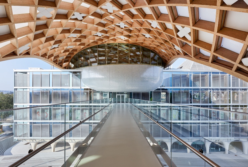 View of the Cité du Temps museum building from the bridge. The timber lattice structure forms the roof.